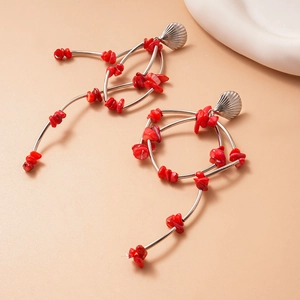 Bohemian silver shell earrings with irregular red coral stones on a soft beige surface
