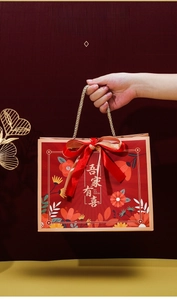 Red paper wedding favor bag with golden handles and a large decorative silk bow