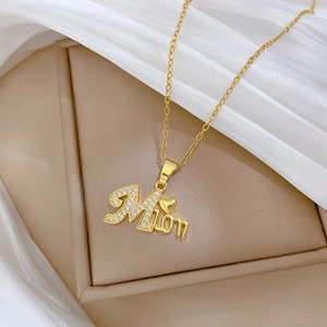 Detail of gold crystal MAMA pendant necklace on beige jewelry box with silk