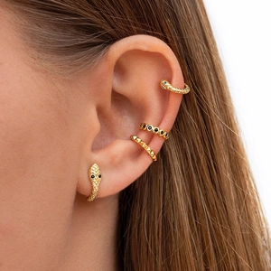 Detail shot of golden snake earring and ear cuffs with black stones on female model