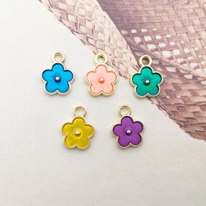 Detail of five colorful enamel flower pendants with gold borders for DIY jewelry making