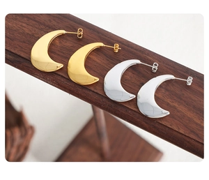 Détails macro de boucles d'oreilles croissant de lune en acier poli doré et argenté