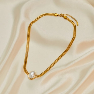 Close-up of golden braided stainless steel necklace with round pearl on silk background