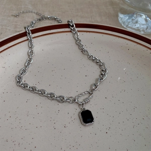 Detail of silver chain necklace with rectangular black opal pendant on ceramic plate