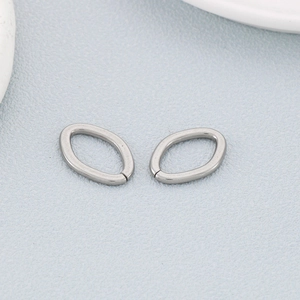 Macro shot of silver stainless steel oval geometric DIY jewelry accessories on light blue background
