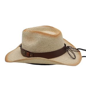 Detail of western straw hat with brown leather band and vintage metal emblem accent