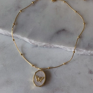 Vintage gold-plated necklace with oval shell pendant featuring a butterfly relief motif