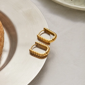 Detailed view of gold rectangular woven texture earrings on a metal plate