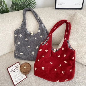 Close-up of knit tote bag featuring white bow embroidery and classic plaid lining detail