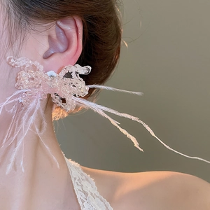 Detail of pink beaded butterfly earring with soft white feathers worn by a model