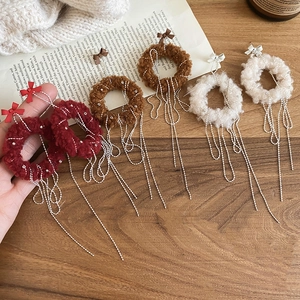 Detailed shot of plush tassel earrings in red brown and white with metal chains