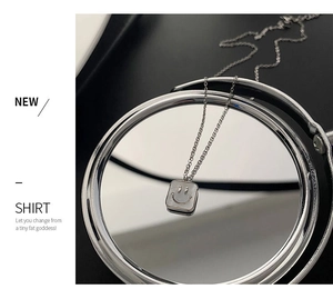Close-up of silver titanium steel necklace with a shell smiley face pendant on a mirror