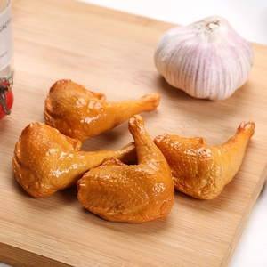 Realistic PVC roasted chicken drumstick models displayed on a wooden cutting board