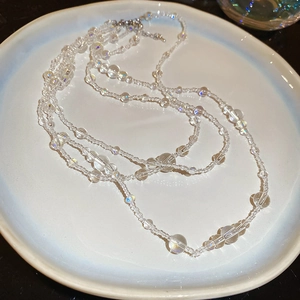 Macro shot of layered iridescent glass beads on a ceramic plate for women necklaces