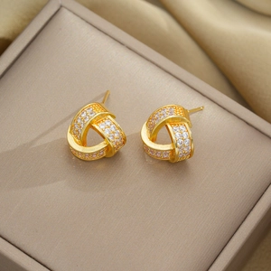 Detailed view of geometric triangle gold earrings with zircons in a beige jewelry box