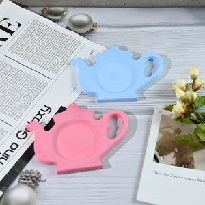 Macro shot of blue and pink teapot-shaped silicone resin coasters on a textured wooden table