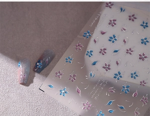 Dettaglio adesivi per unghie 3D con fiori blu e decorazioni di perle