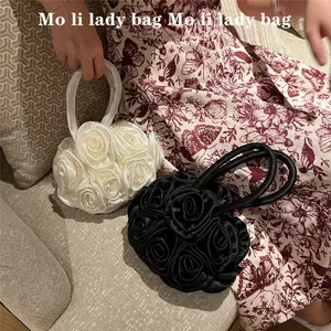 Detail of 3D rose flower evening bag in black and pearl white with round handle