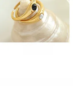 Close-up of gold plated rings featuring a white pearl and black oval gemstone detail