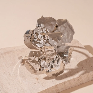 Macro detail of silver irregular pleated flower cuff with hammered metal texture