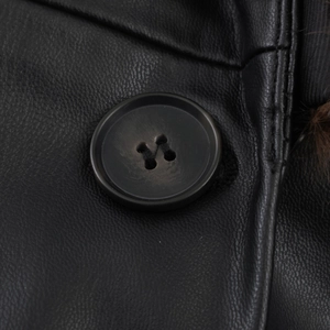 Close-up of black leather coat texture featuring a classic four-hole button and refined grain