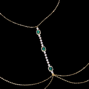 Detail of gold body chain with emerald square crystals and shimmering rhinestones