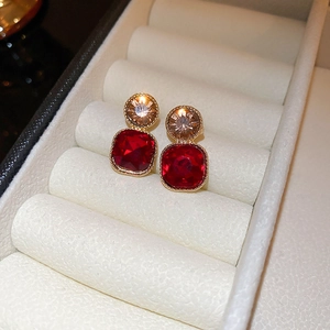 Elegant gold flower stud earrings with red and champagne zircon crystals in a jewelry box