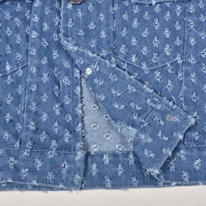 Close-up of blue denim vest showing detailed distressed texture and ripped flower patterns
