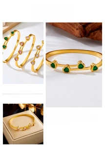 Detailed macro view of heart-shaped zircon gold-plated bangles in green, pink, and white