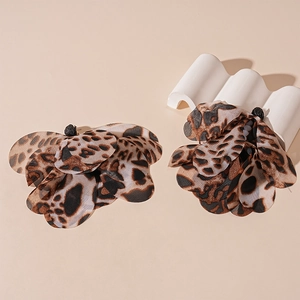 Detailed close-up of leopard print fabric flower earrings with layered petals and black stamens