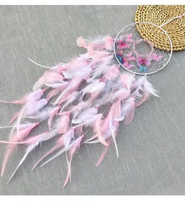 Close-up of handmade pink dream catcher with soft feathers and butterfly detail