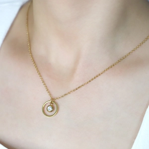 Close-up of gold geometric circle pendant necklace with birthstone on model's neck