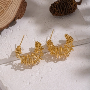 Detailed macro view of gold-plated coiled wire earrings on a white stone background