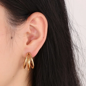 Close-up of a model wearing elegant triple-layered golden C-shaped hoop earrings