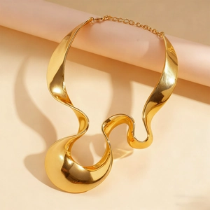 Close-up of golden irregular liquid flow metal necklace on aesthetic pink pedestal