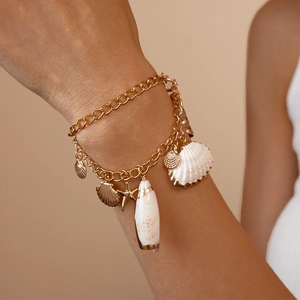 Golden layered ocean-style charm bracelet with starfish and shell pendants on wrist