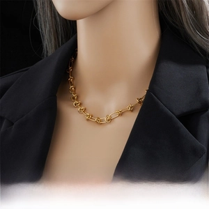 Close-up of gold knotted link chain necklace in punk style worn on a black suit blazer