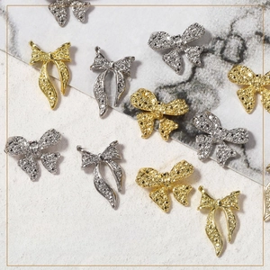 Makroansicht von gold- und silberfarbenen Schleifen-Nagel-Charms mit Diamanteffekt