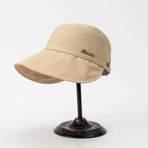 Detail view of beige sun hat featuring breathable woven crown and elegant metal logo