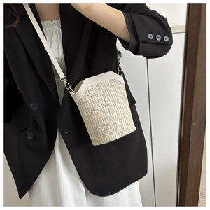 Détail du sac seau en paille tressée avec broderie florale et sangle en cuir