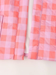 Macro shot of pink and orange gingham vest showing stitching and white lining detail