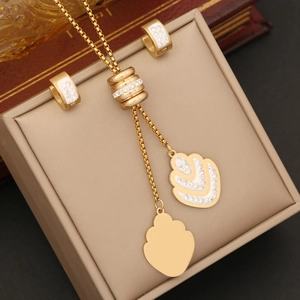 Detailed view of gold leaf pendant necklace and matching hoop earrings with white zircon