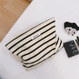 Detailed top view of striped cotton makeup bag with simple wish label on quilted surface