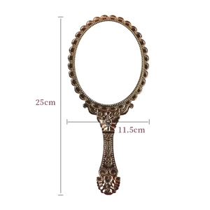 Vintage bronze handheld mirror with ornate floral engravings measuring 25cm by 11.5cm