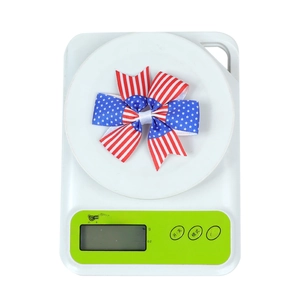 Detail view of American flag bow hair clip weighing 4.3g on a digital scale