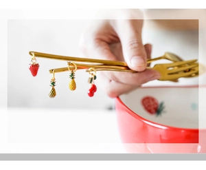 Detail of golden chopsticks with decorative strawberry and pineapple fruit charms