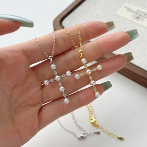Detail of cross pendants with white pearls and rhinestones in gold and silver finish