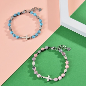 Close-up of pink zebra stone and turquoise beaded bracelets with steel cross charm.