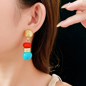 Detail of vintage bohemian earrings with gold texture, red beads and turquoise stones