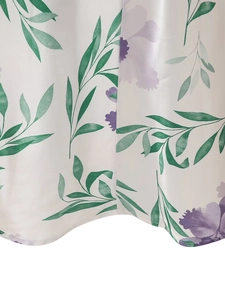 Détail d'une robe en soie montrant des feuilles vertes et des fleurs mauves sur fond blanc